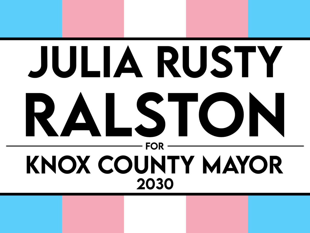A trans flag sign that says "JULIA RUSTY RALSTON FOR KNOX COUNTY MAYOR 2030"
